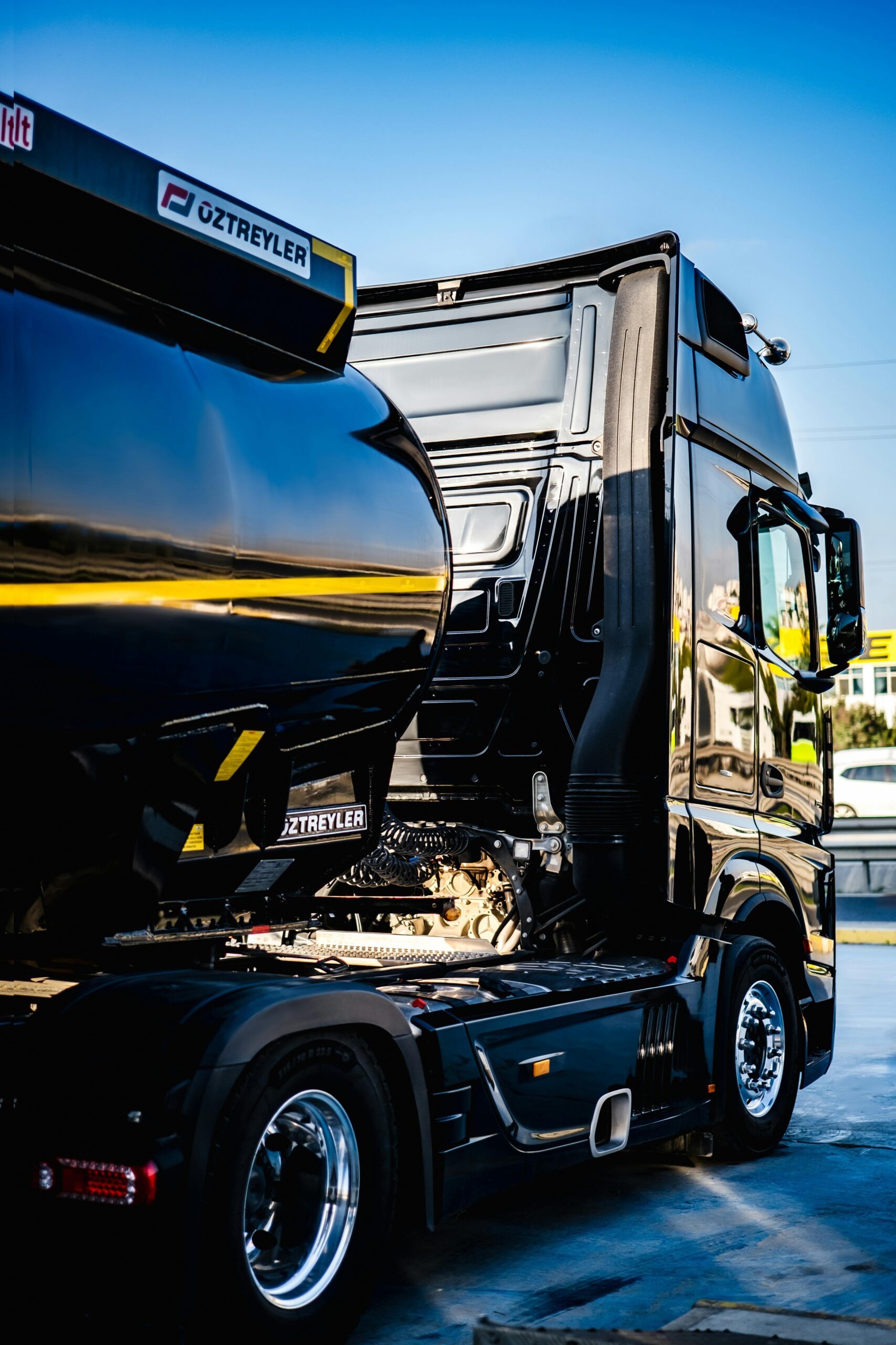 Black semi truck ready for cargo loading at an industrial dock.