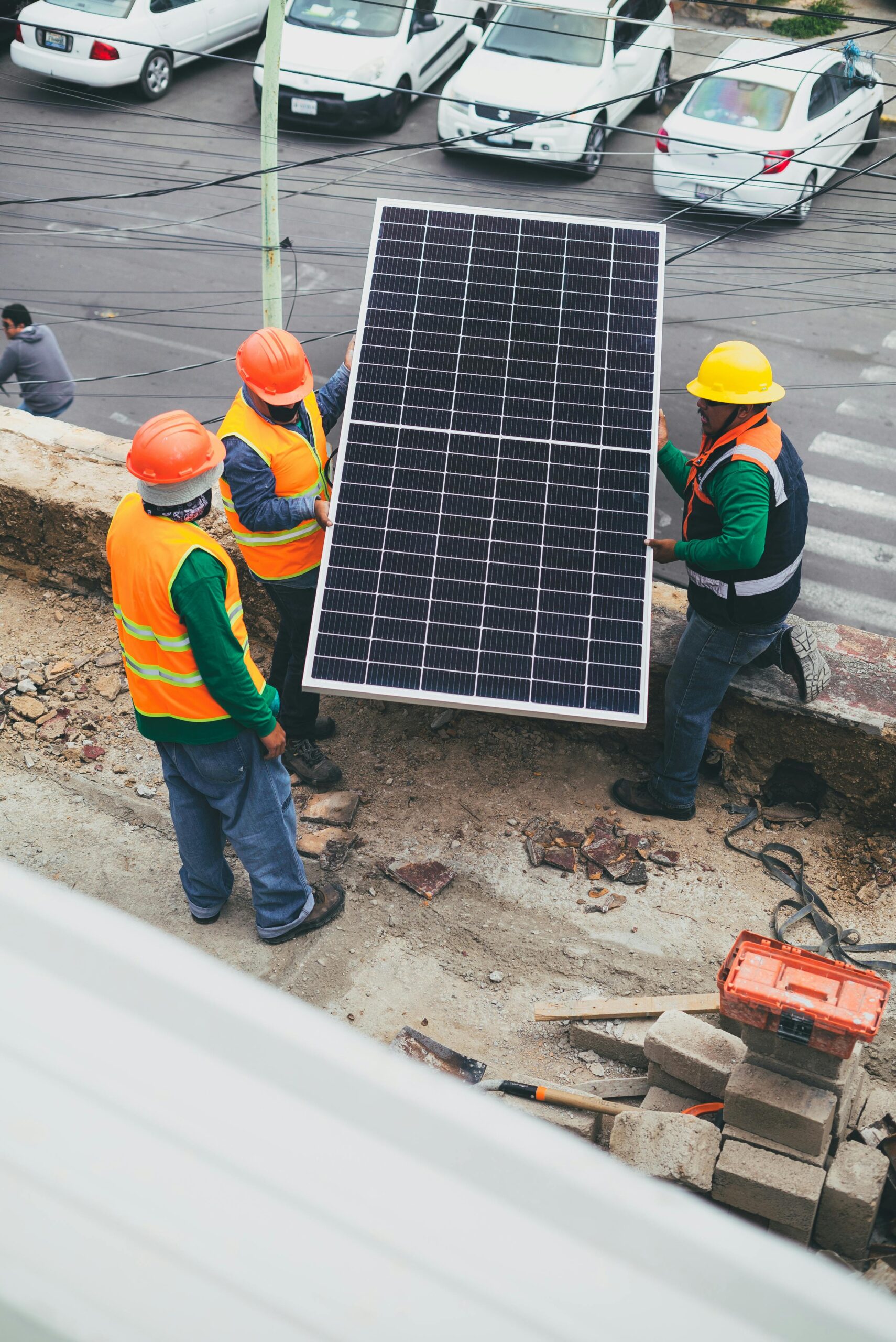 Workers in safety gear installing a solar panel outdoors.